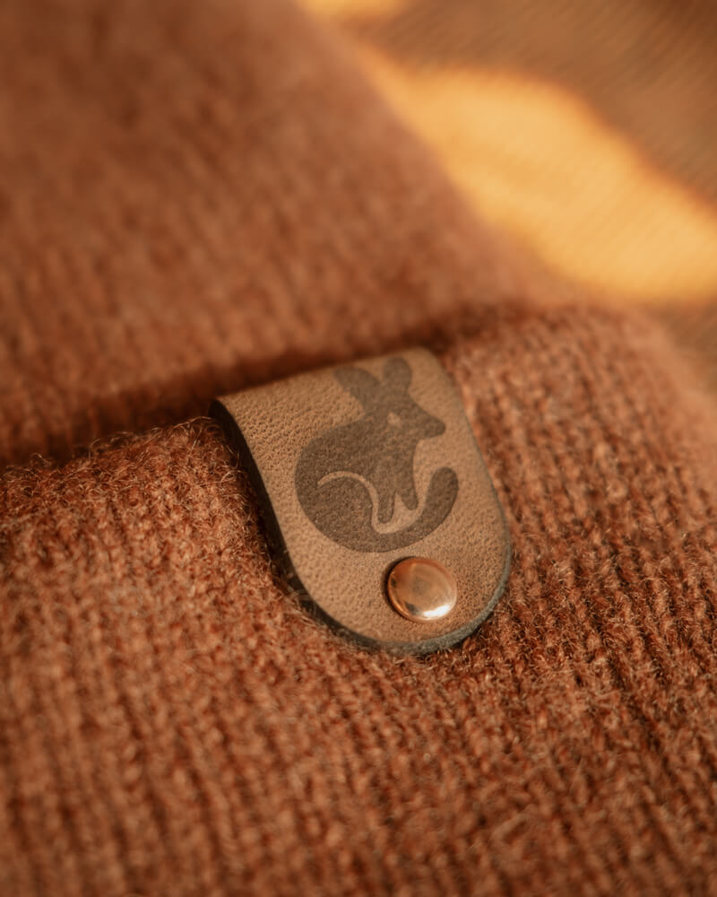 Close-up of a brown textured fabric with a leather patch featuring a bilby emblem.