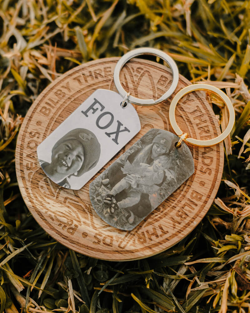 Keychain with engraved dog tags and wooden disc on grass