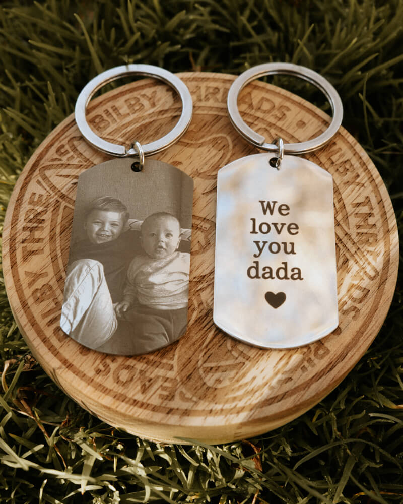 Keychain with photo of two children and 'We love you dada' text on a wooden disc with engraved text.